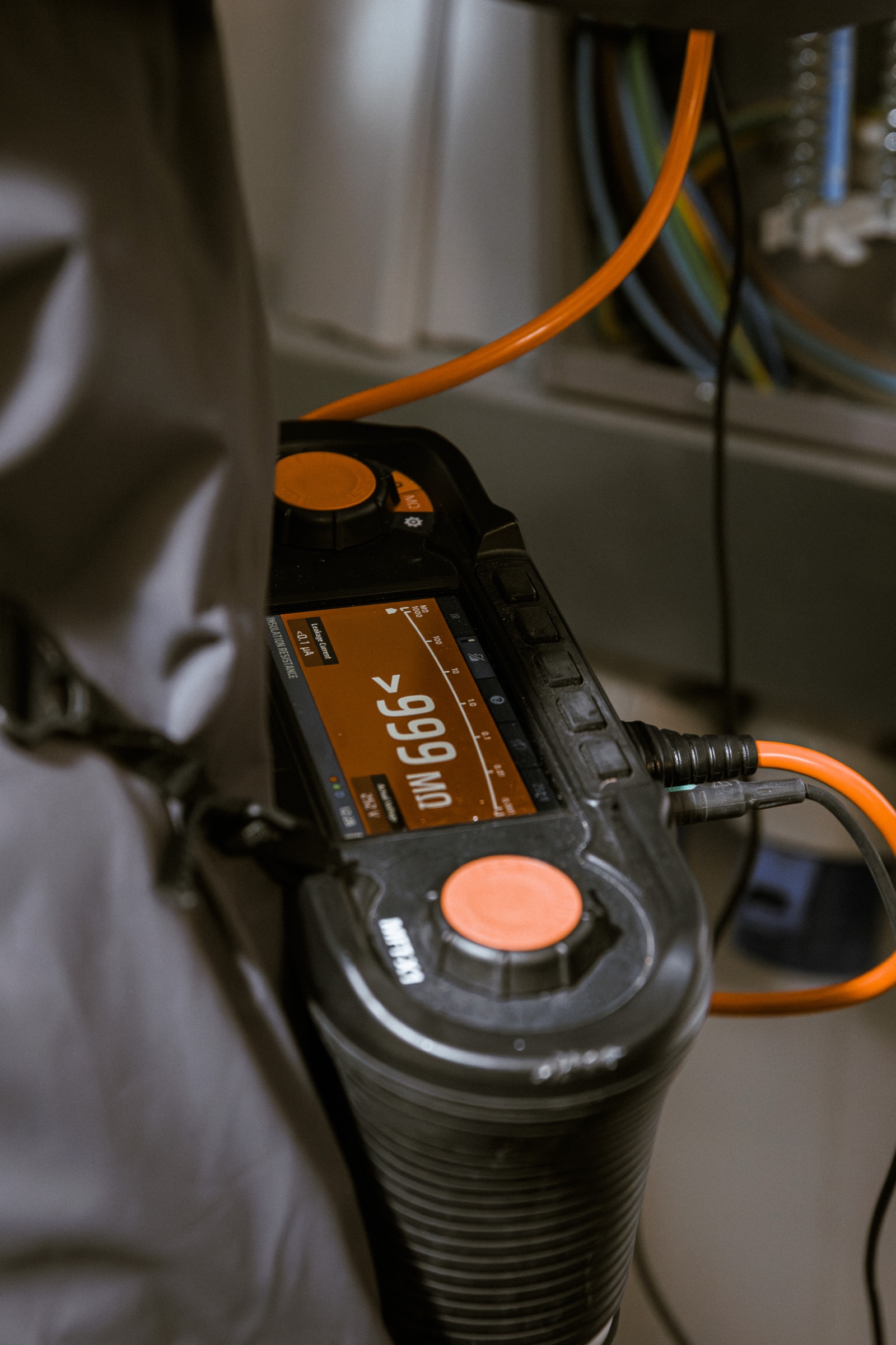 A multifunction insulation tester showing a 999 MΩ result during a periodic inspection — the textbook compliance image.